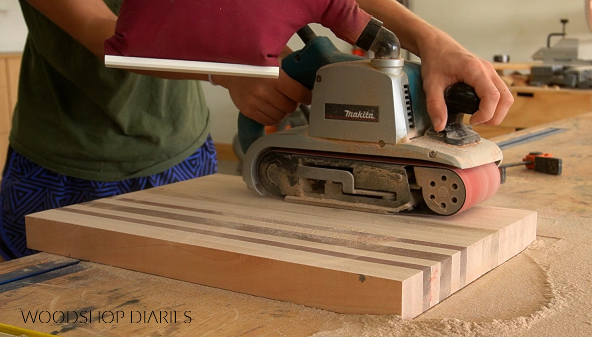 Shara Woodshop Diaries using a belt sander on a cutting board