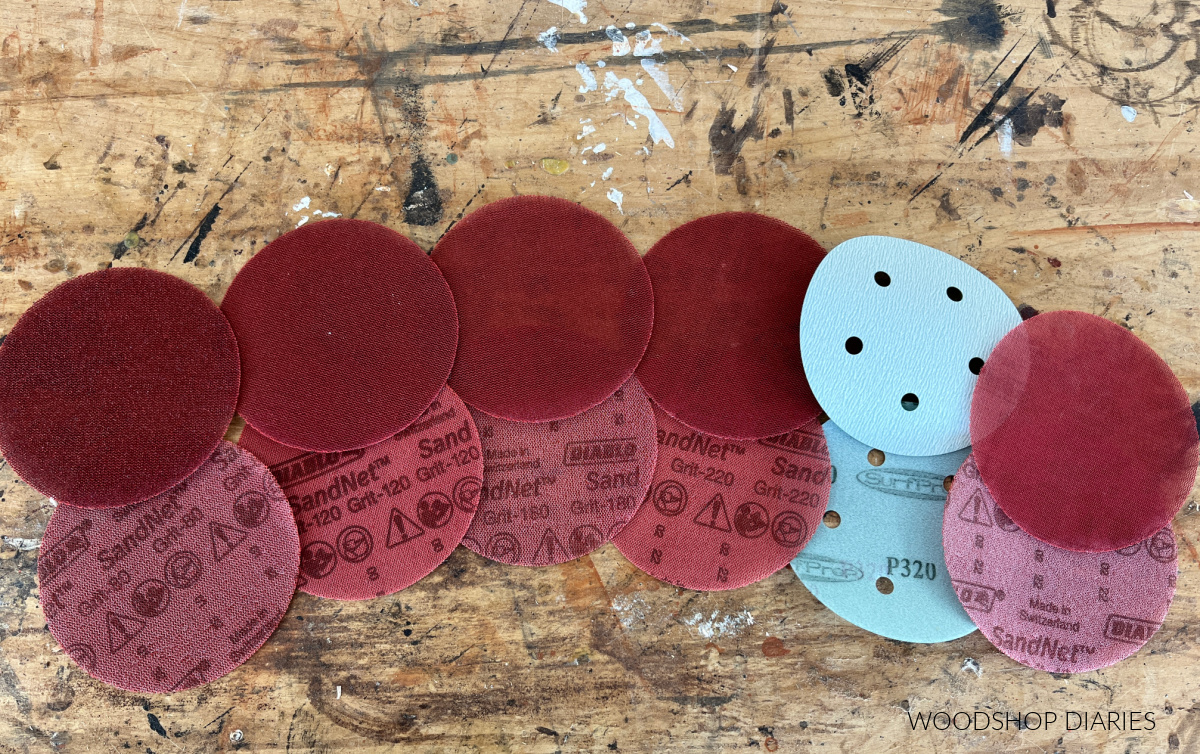 sandpaper discs laid out on workbench from 80 grit on the left up to 400 grit on the right