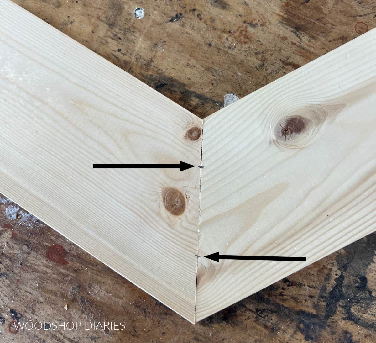 30 degree mitered board ends together on workbench with two small marks on joint