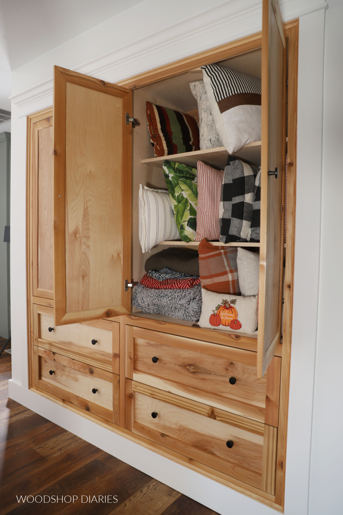 Completed built in closet cabinets with drawers at bottom and doors on top--one set of doors open to reveal shelves inside