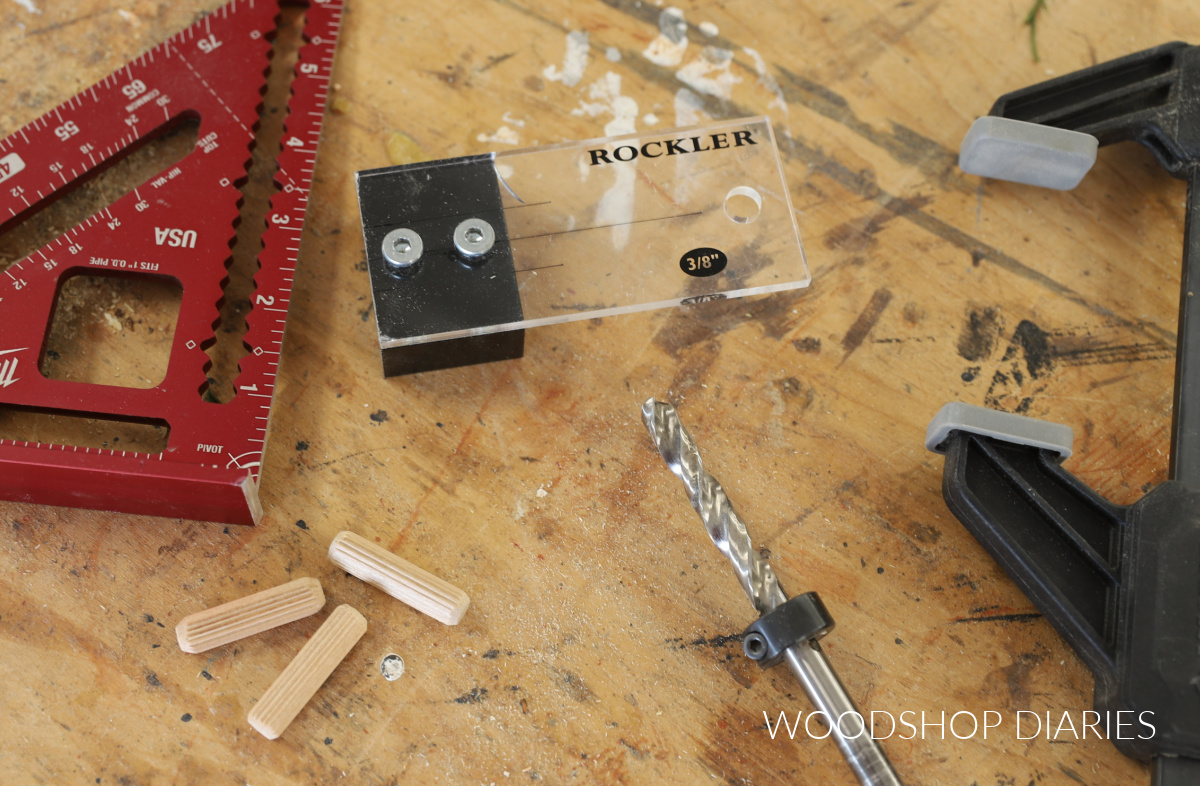 Dowel jig, square, dowel pins and clamp on workbench top