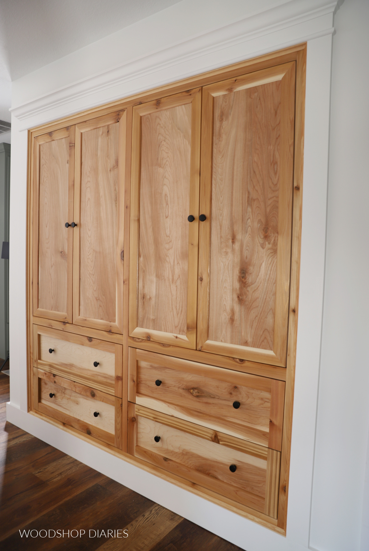 Completed cabinet built ins with four doors at top and four drawers at bottom built into hallway closet opening