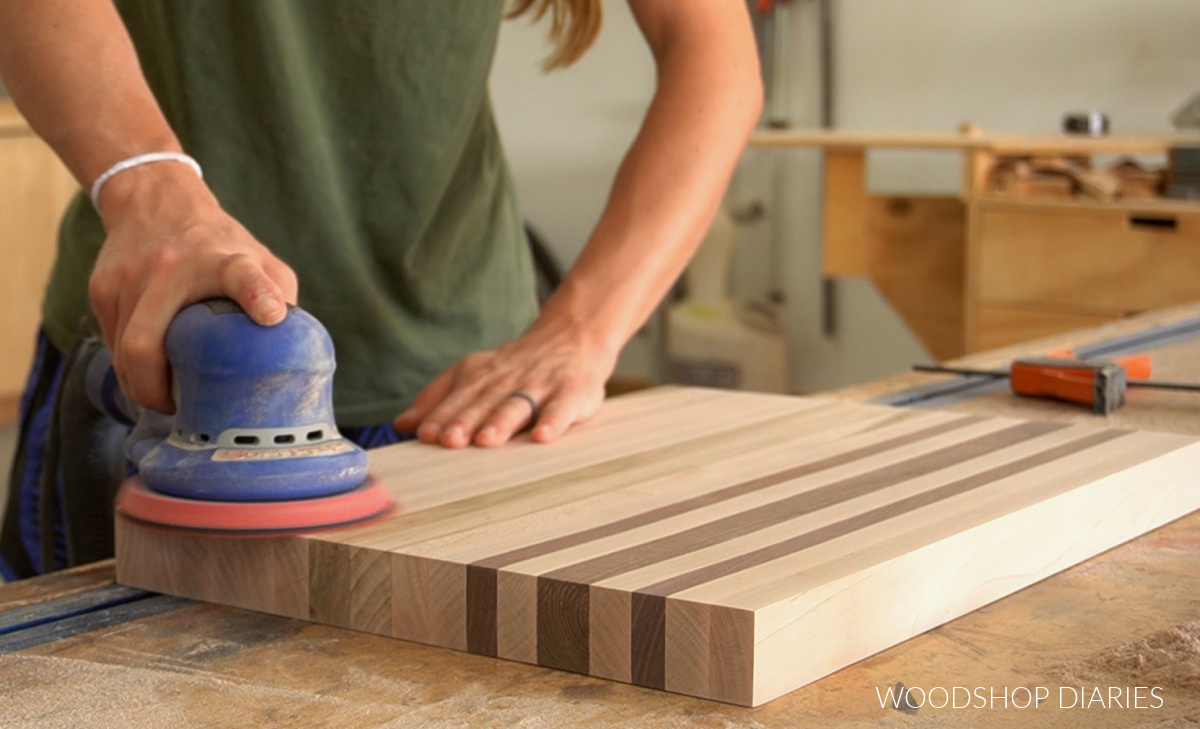 orbital sander sanding cutting board on workbench