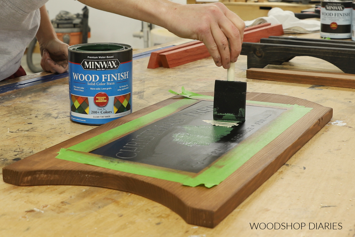 Shara Woodshop Diaries applying green stain to Christmas tree stencil on wood board