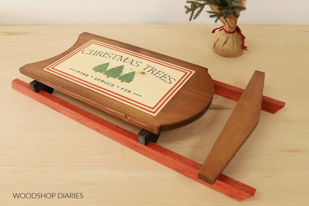Completed wooden Christmas Sled decoration on table top with faux Christmas tree