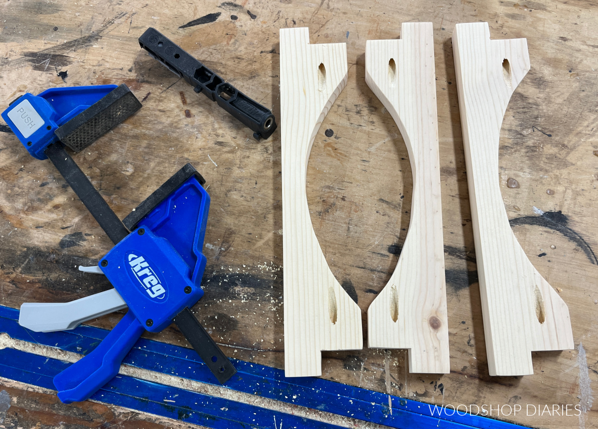 Sled runner pieces cut to shape laid on workbench with pocket holes drilled into the ends. Kreg Micro Pocket hole jig laying next to boards with Kreg Clamp