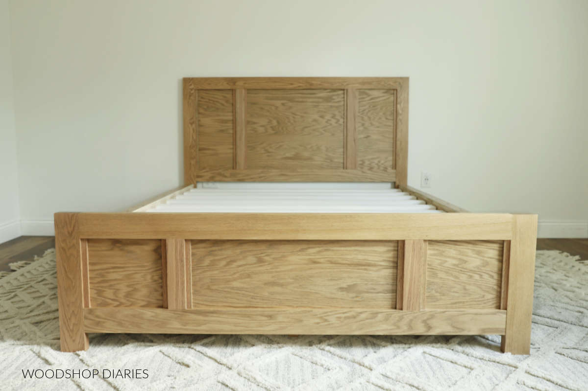 DIY Oak storage bed assembled with slats against white wall--no mattress on top yet