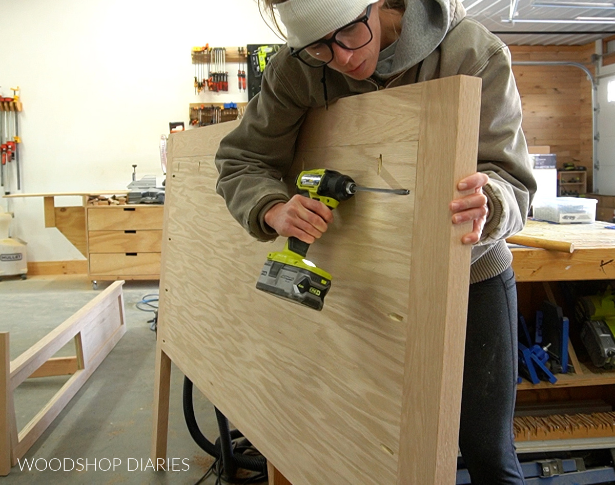 Shara Woodshop Diaries installing plywood panel into headboard frame with pocket holes and screws