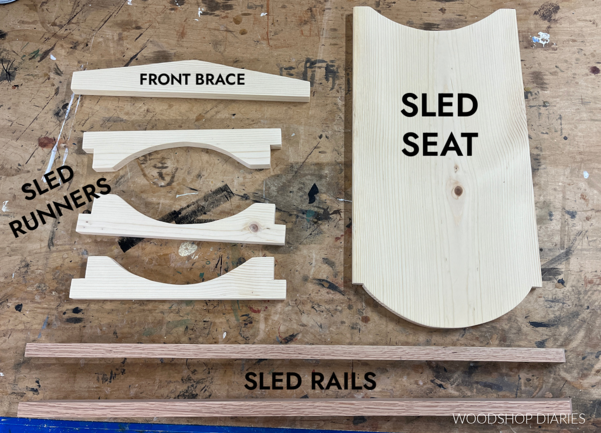 Wooden sled pieces cut and shaped laid out on workbench ready to assemble