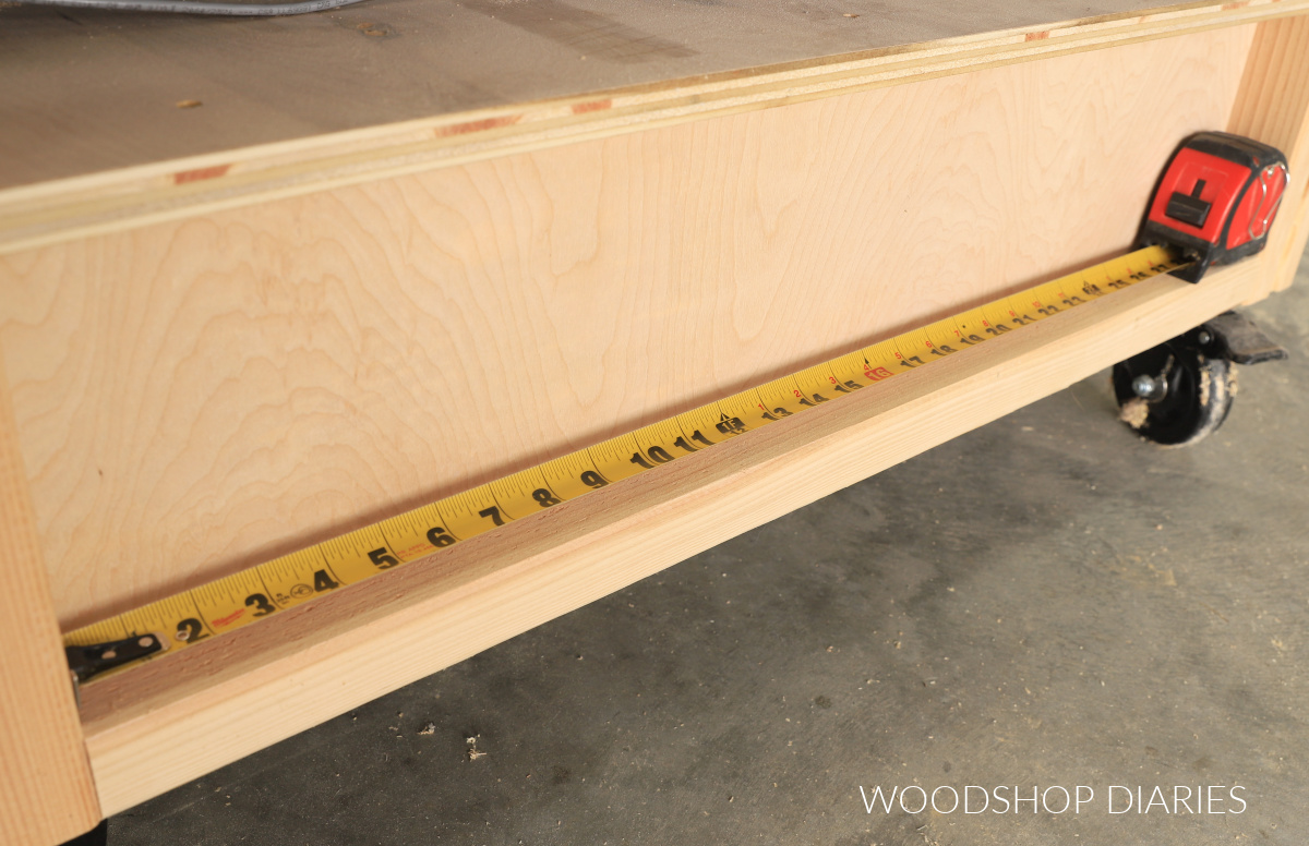 Tape measure extended to measure inside opening of workbench
