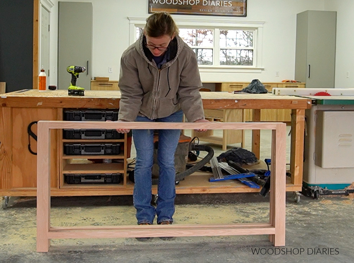 Shara Woodshop Diaries holding dresser frames assembled in front of workbench
