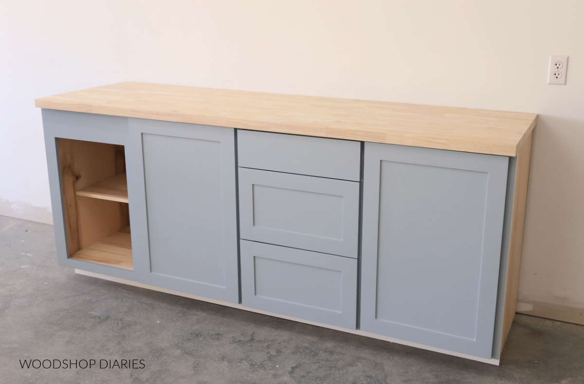 four base cabinets painted SW Stardew with butcherblock countertop--one open cabinet, two with doors and one with drawers