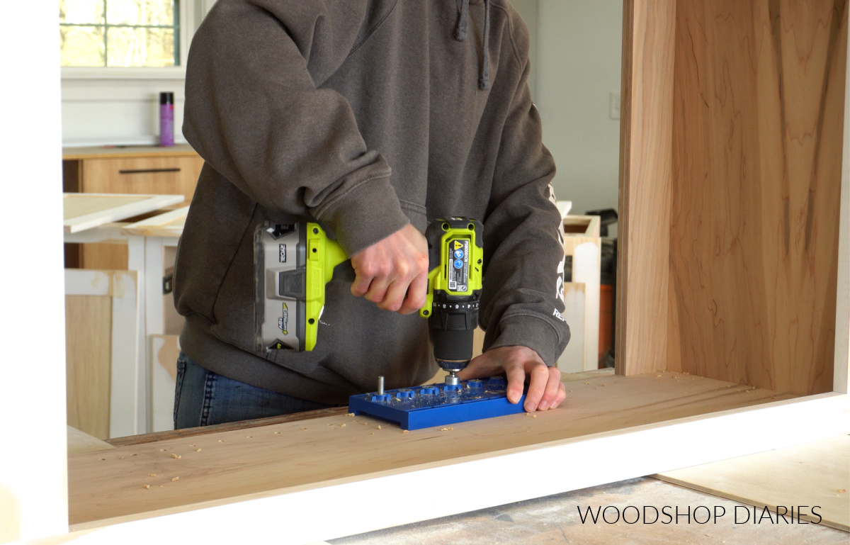 Shara Woodshop Diaries drilling shelf pin holes with a shelf pin jig into the sides of cabinet box