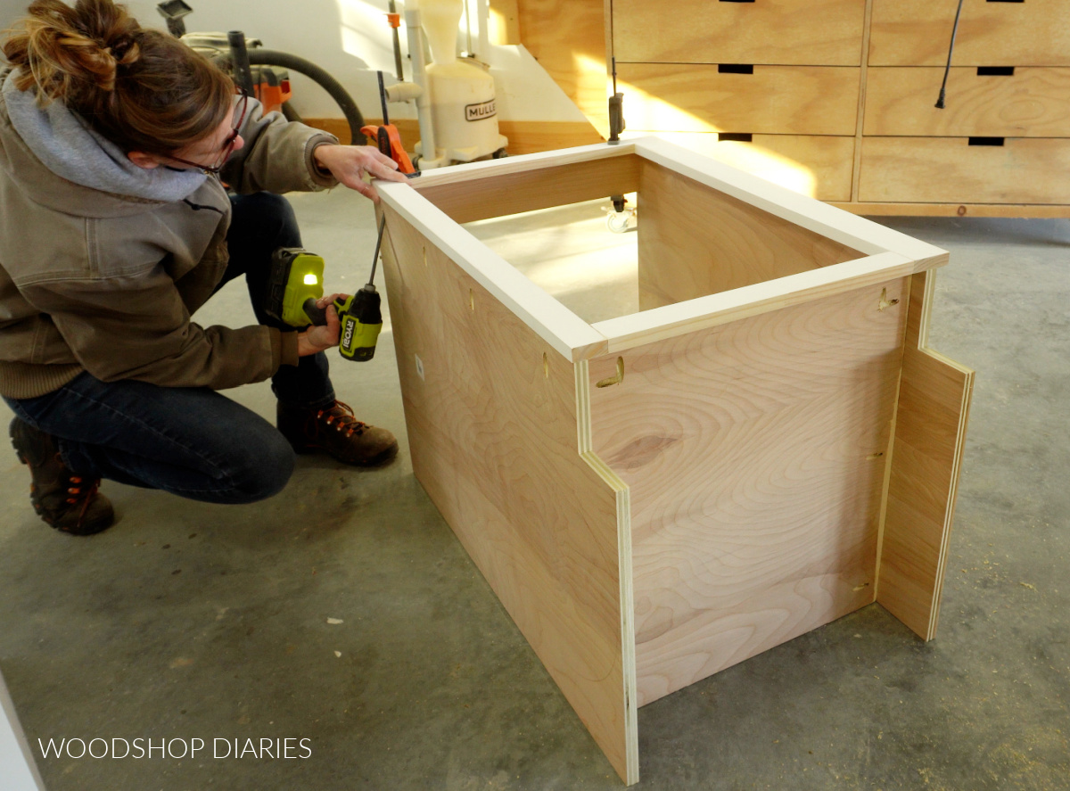 Shara Woodshop Diaries installing face frame onto front of base cabinet with pocket holes and screws.
