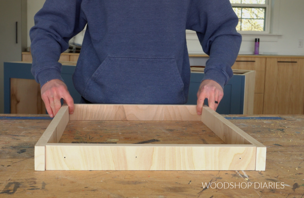 Shara Woodshop Diaries holding boards together in a square on workbench
