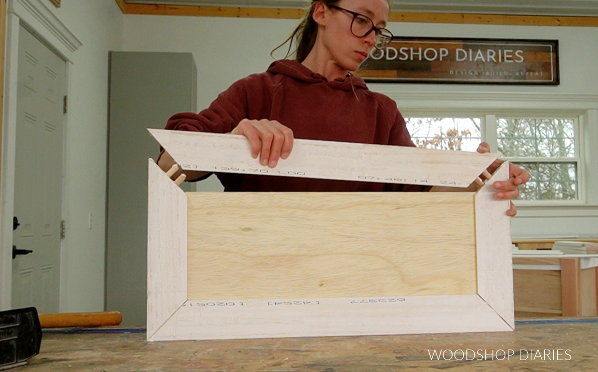 Shara Woodshop Diaries assembling cabinet door using dowel pins in mitered corners on workbench
