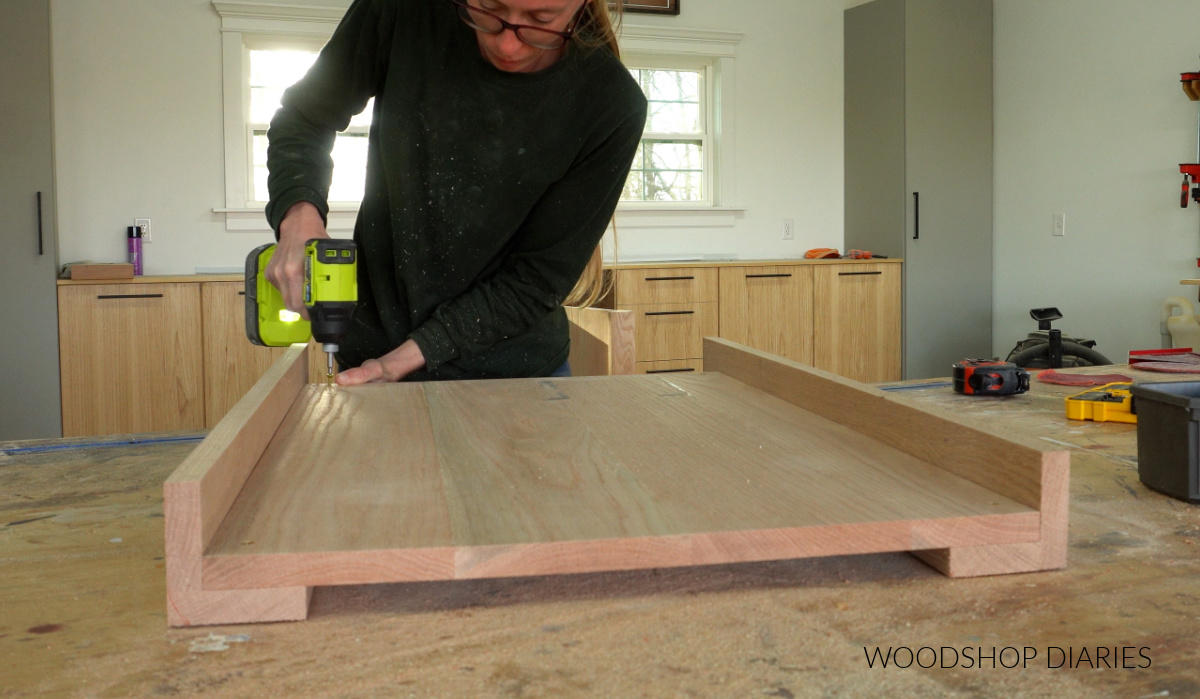 Shara Woodshop Diaries securing side panels to vanity legs on workbench