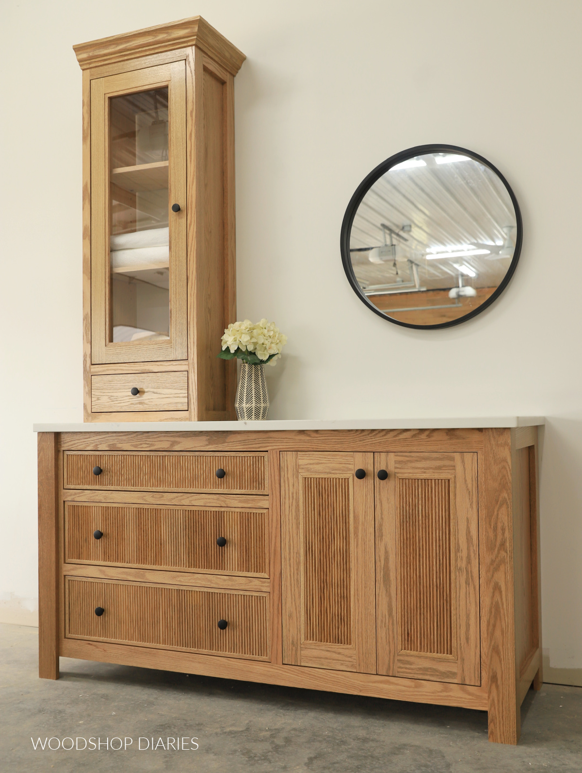 Bathroom vanity with off center sink and tall countertop cabinet with reeded or fluted trim details on the drawer fronts and doors