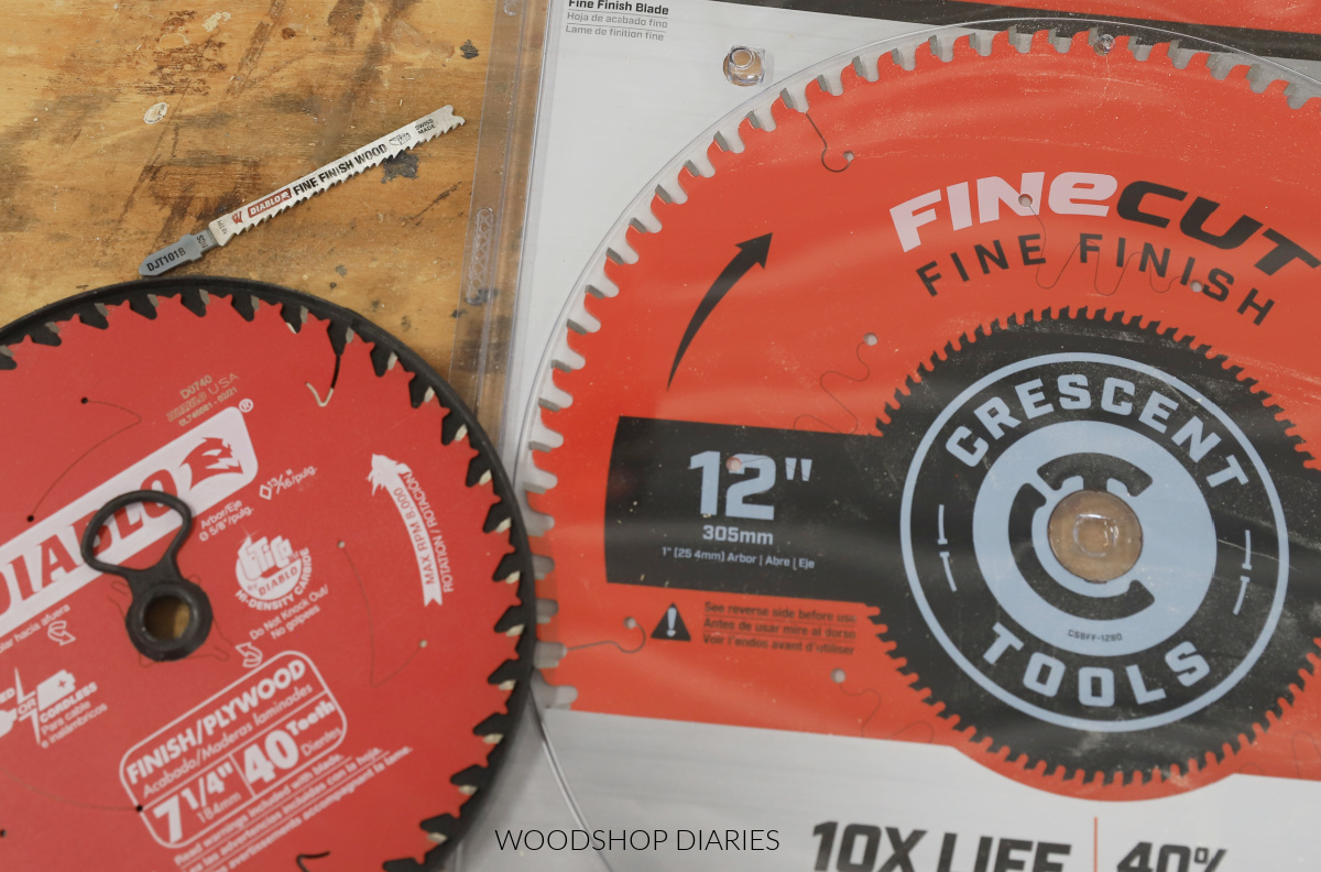 three saw blades laid out on workbench--a fine finish jig saw blade, finish circular saw blade and fine finish miter saw blade