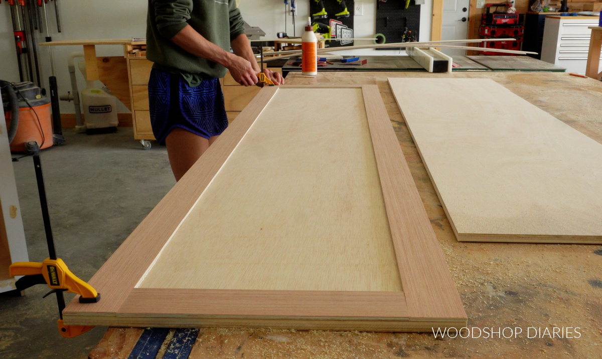 Shara Woodshop Diaries gluing trim onto front of cabinet doors on workbench