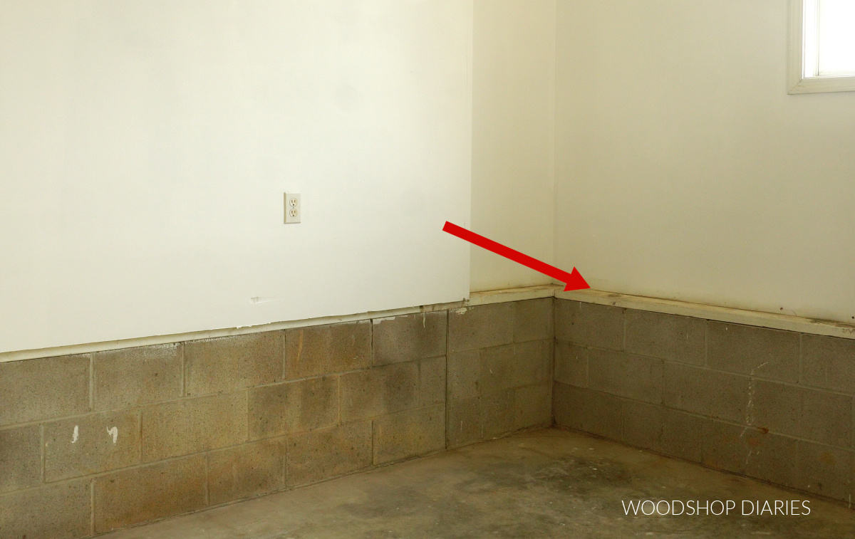 Empty garage wall with arrow pointing to the lip over concrete blocks