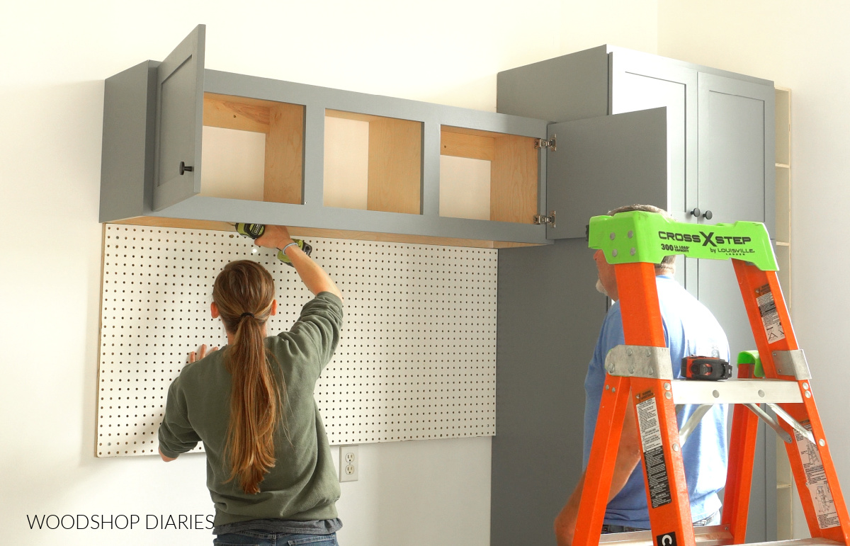 Installing top cabinet in garage makeover above peg board panel
