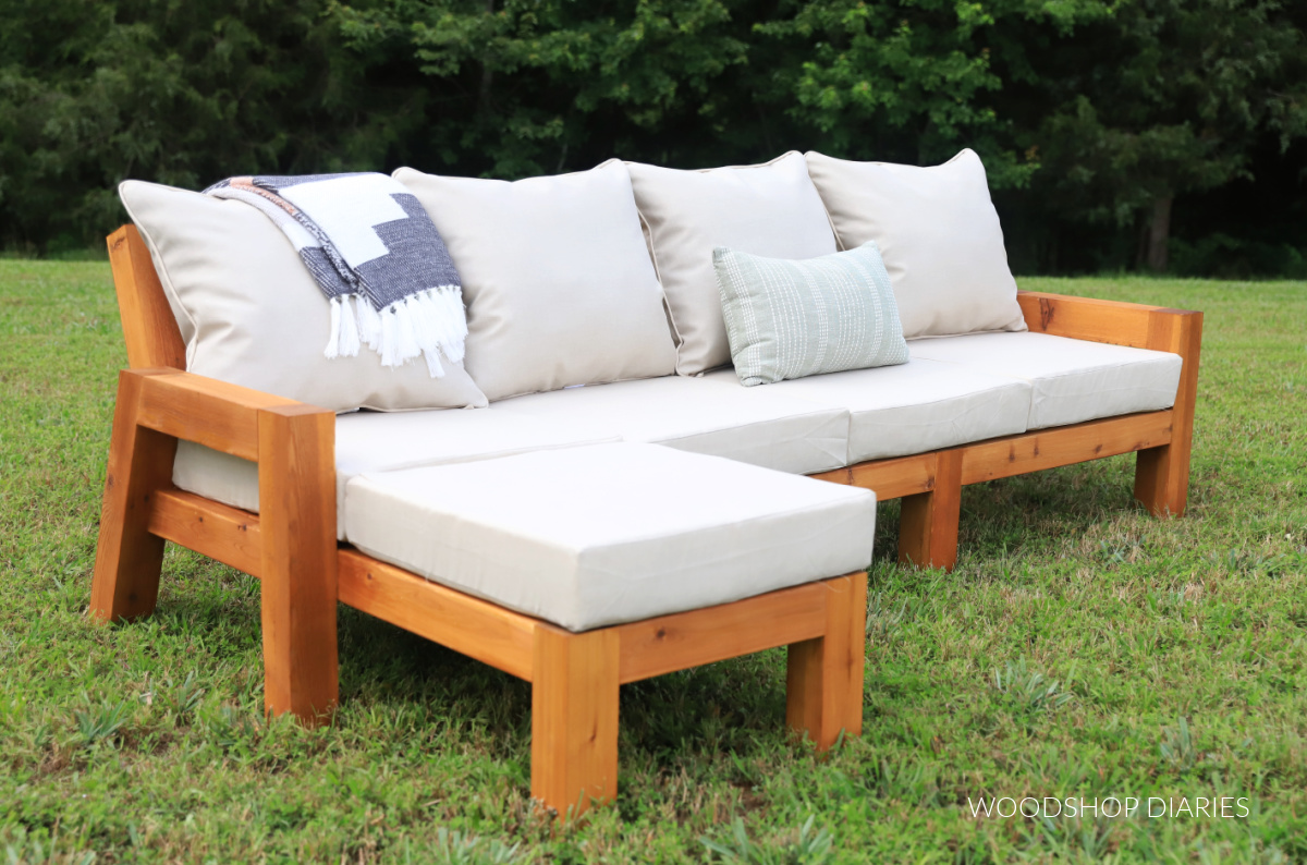 Modern wooden outdoor chaise sectional sofa with tan cushions on grass yard