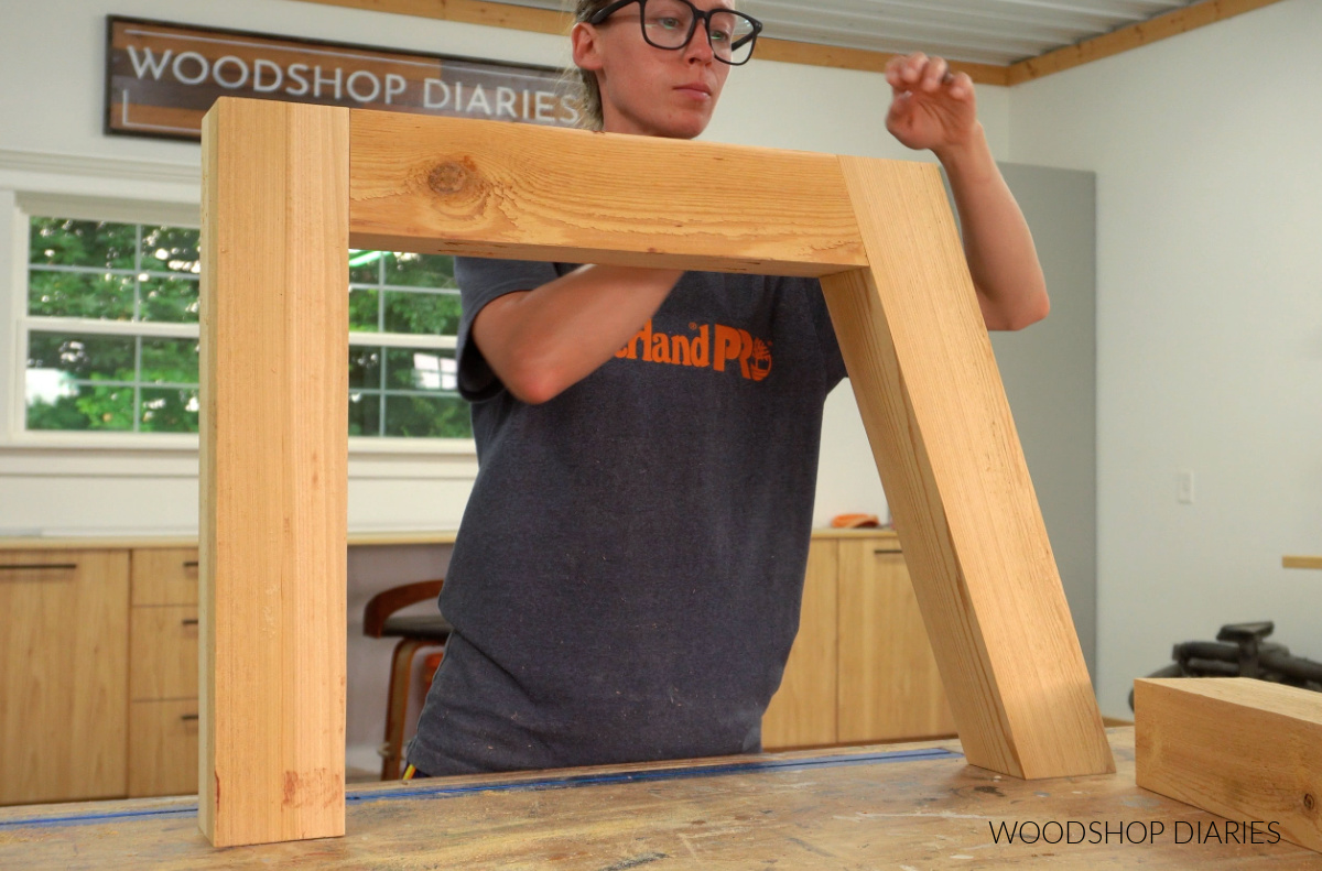 Shara Woodshop Diaries holding arm rest assembling on workbench for chaise chair