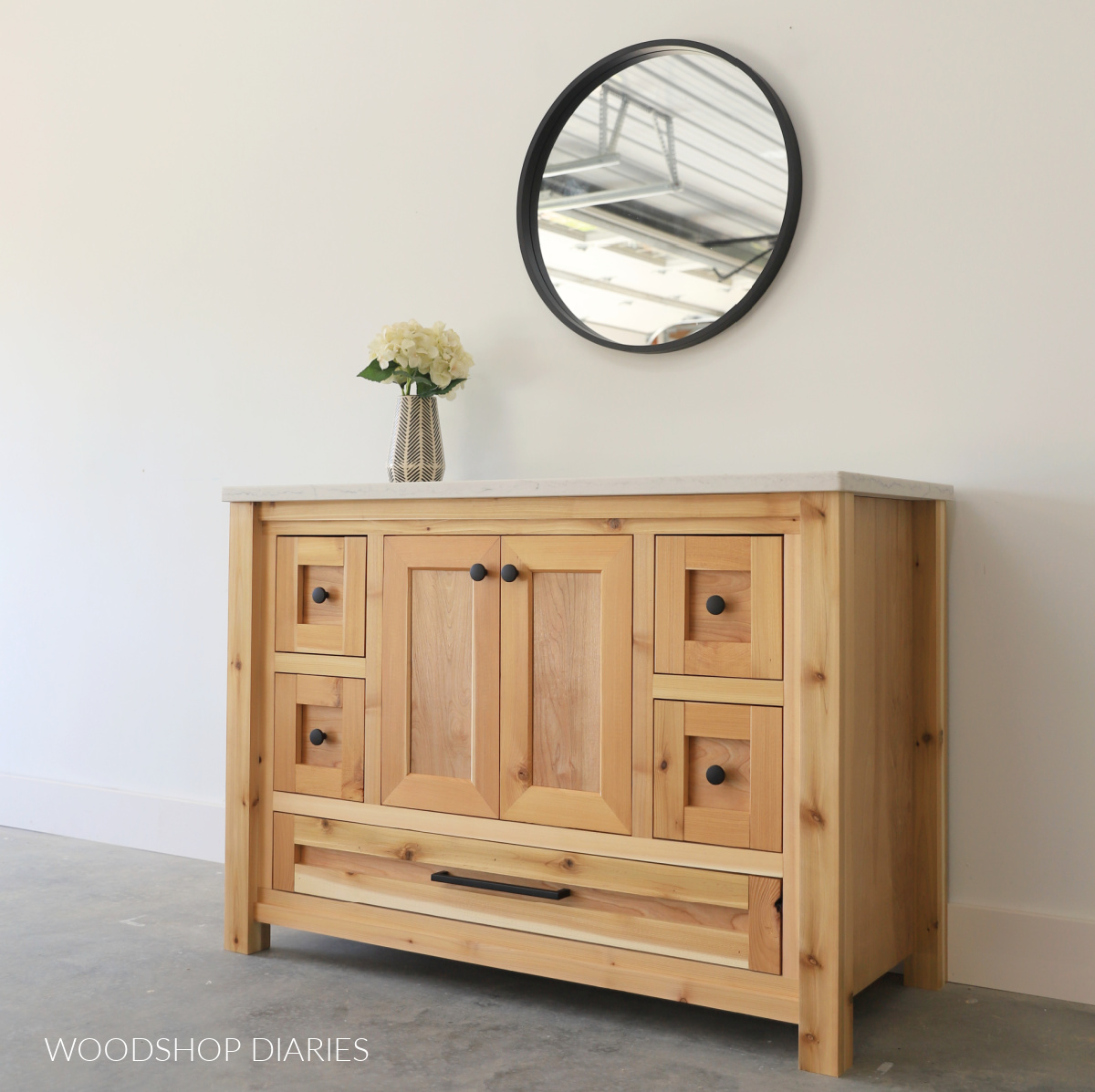 Completed DIY cedar and birch plywood single sink bathroom vanity against white wall with black framed mirror above