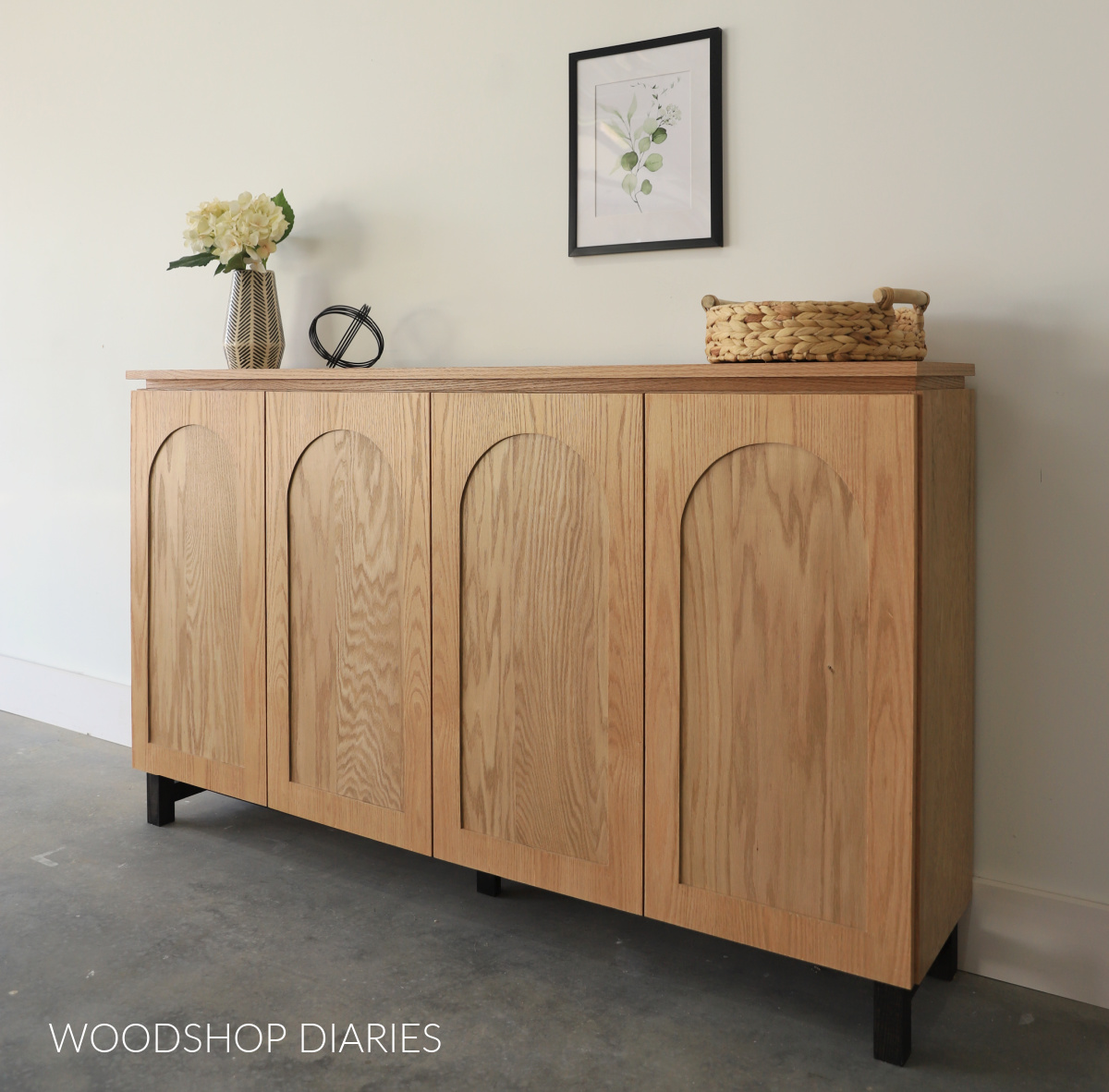 Side board cabinet with 4 doors. Each door has arched cut out on trim. Light stained top cabinet on black stained wooden base