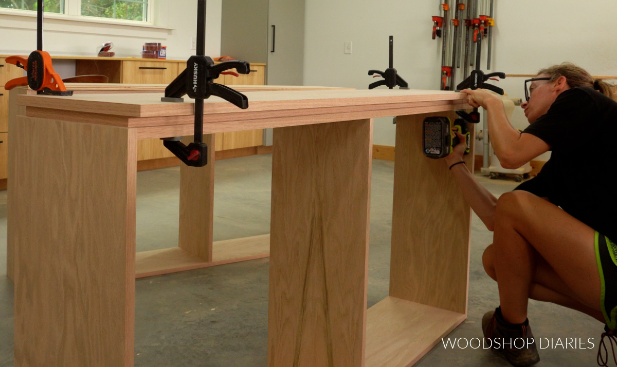 Shara Woodshop Diaries driving screws through top supports of console cabinet to attach top panel