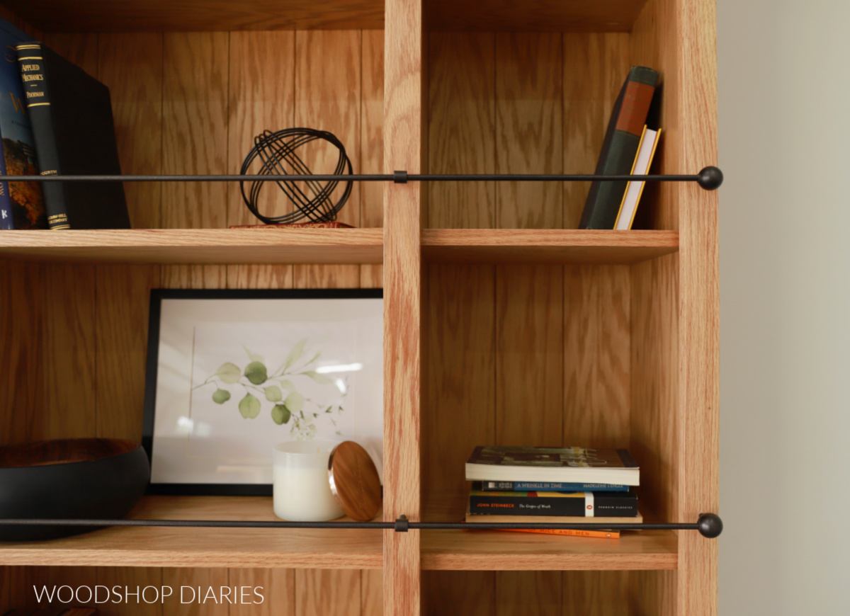 Close up of wooden bookcase with black metallic shelf railing along the front