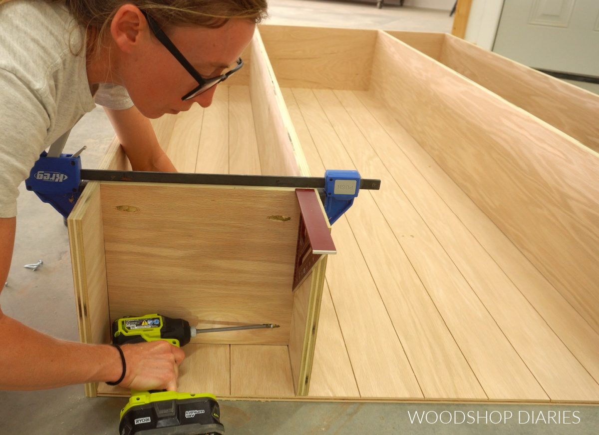Shara Woodshop Diaries driving pocket holes to attach bottom bookshelves to frame