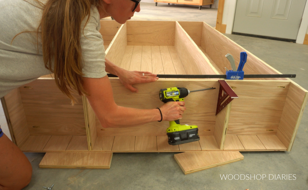 Shara Woodshop Diaries driving screws to attach bottom middle shelf