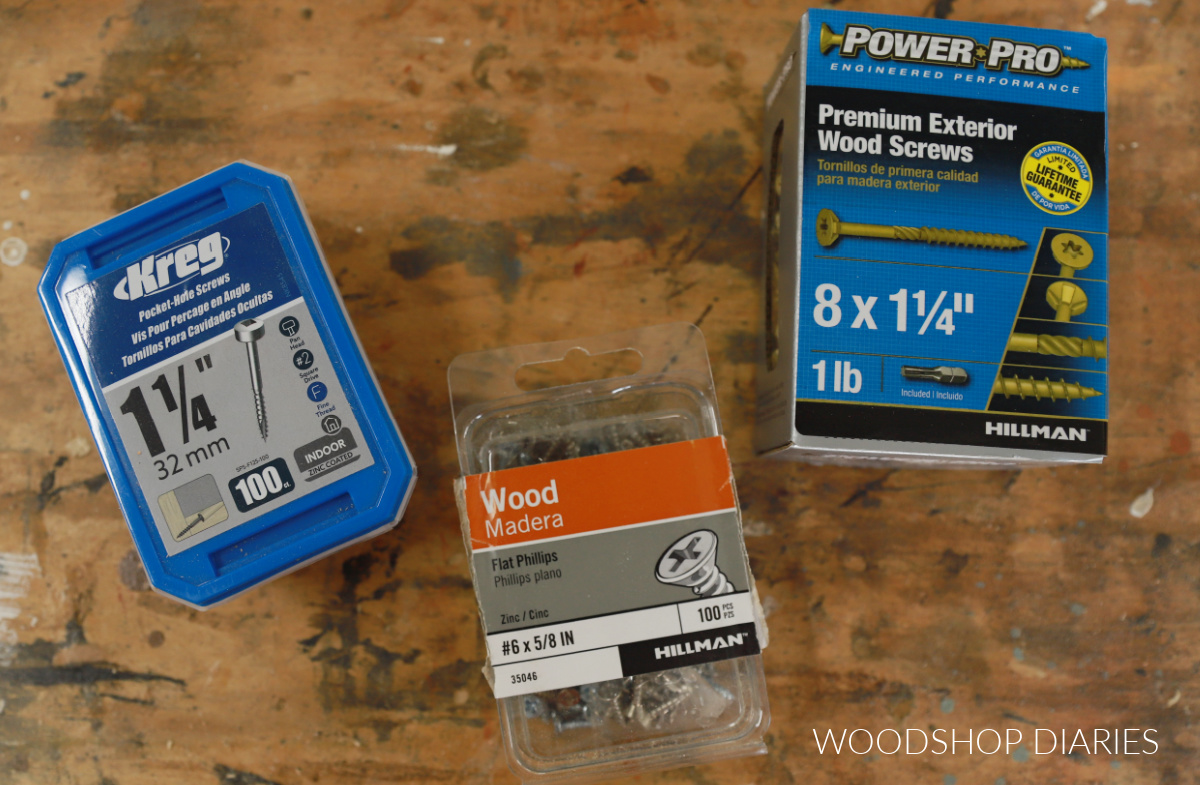 Three different boxes of screws on workbench with labels showing
