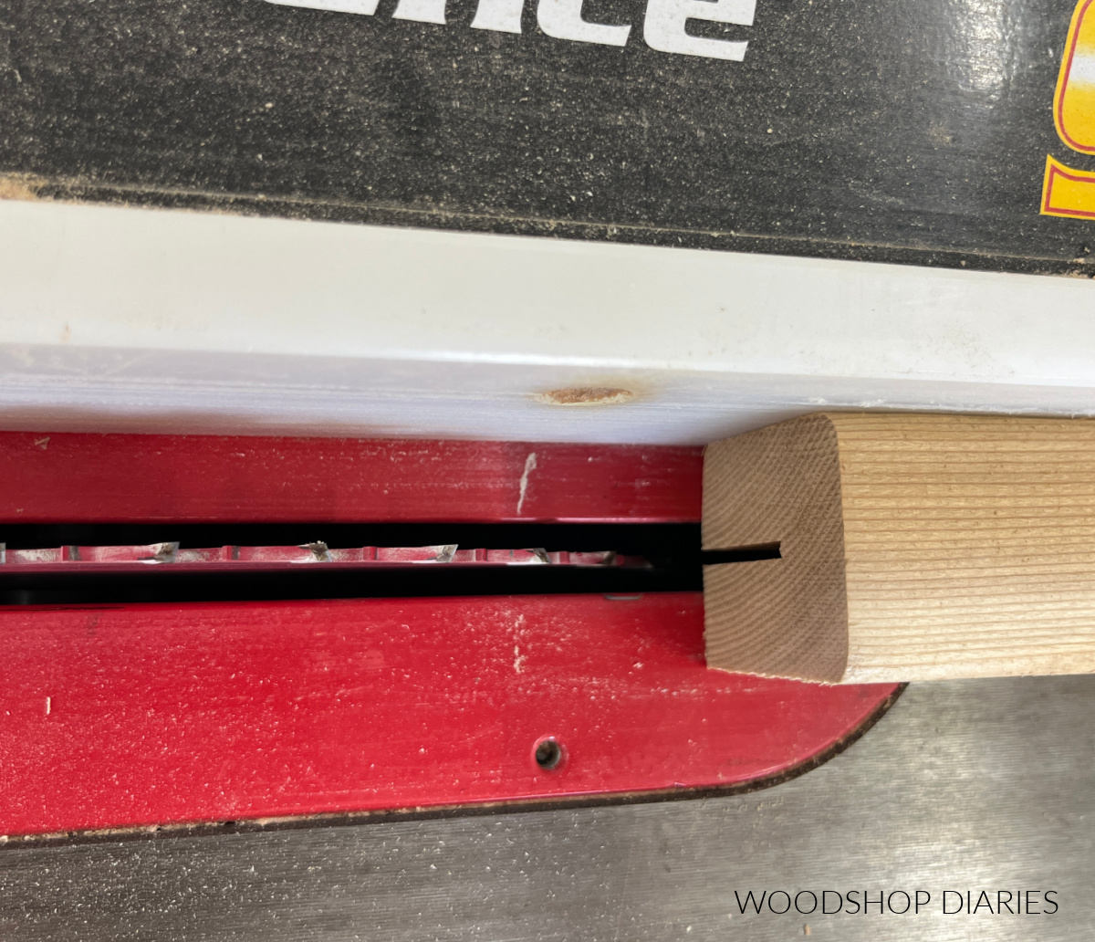 Close up of rip fence adjusted approximately half of board width from saw blade