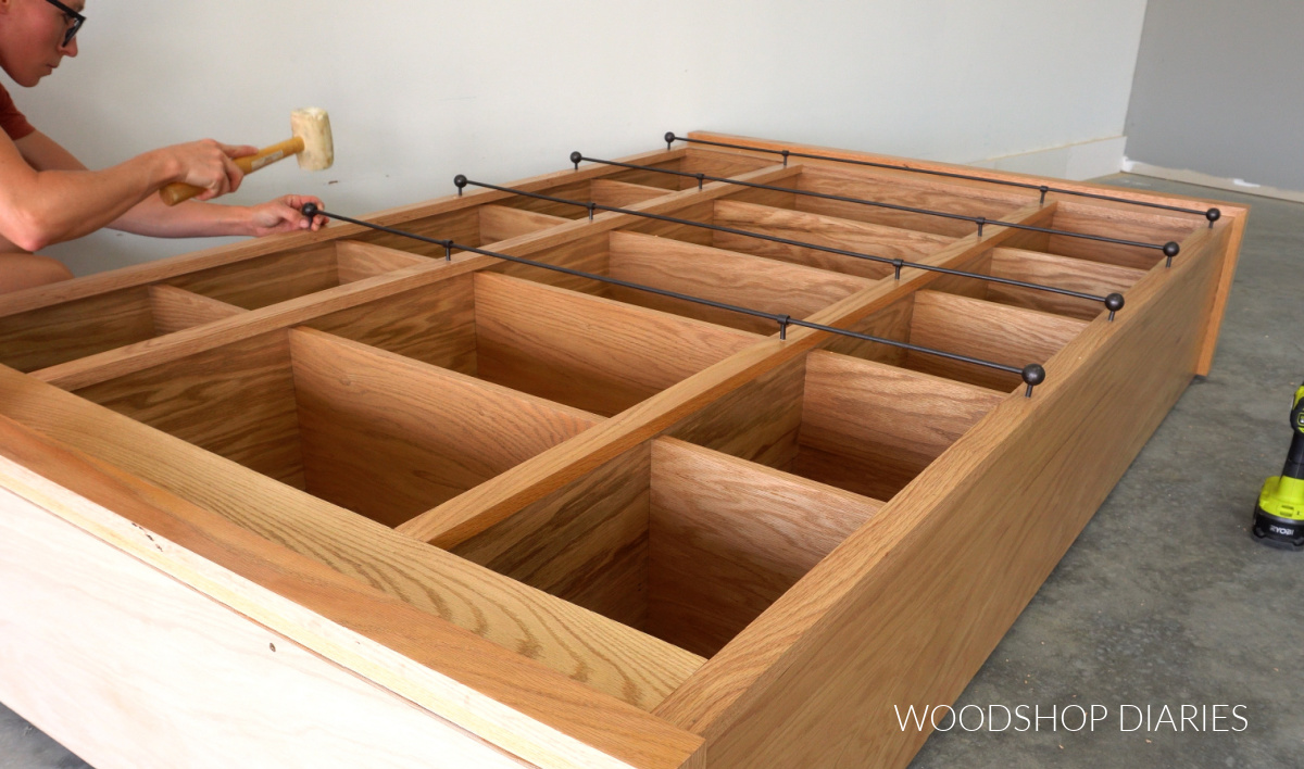 Shara Woodshop Diaries using a rubber mallet to tap DIY shelf railing into bookcase