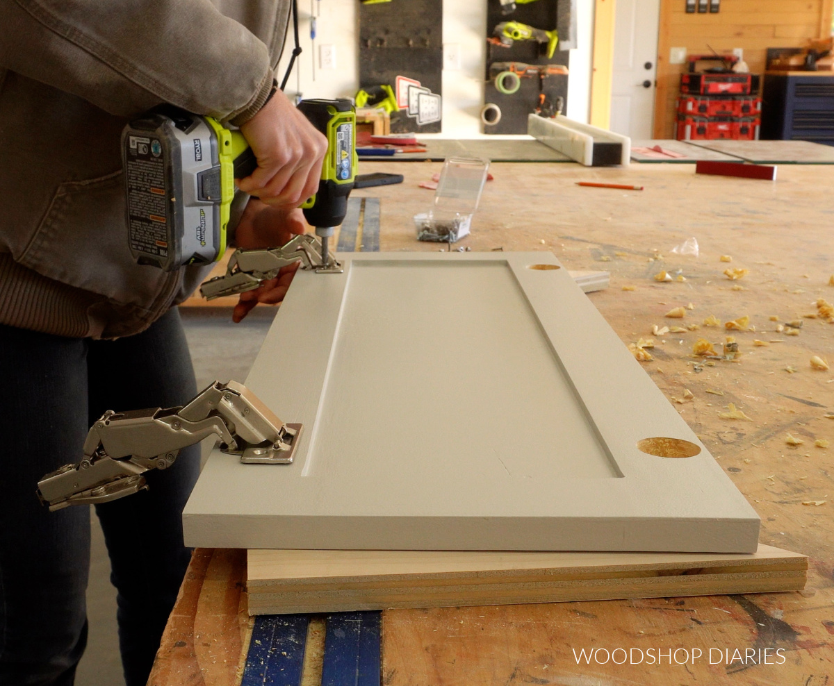 Shara Woodshop Diaries screwing concealed hinges into cabinet door on workbench