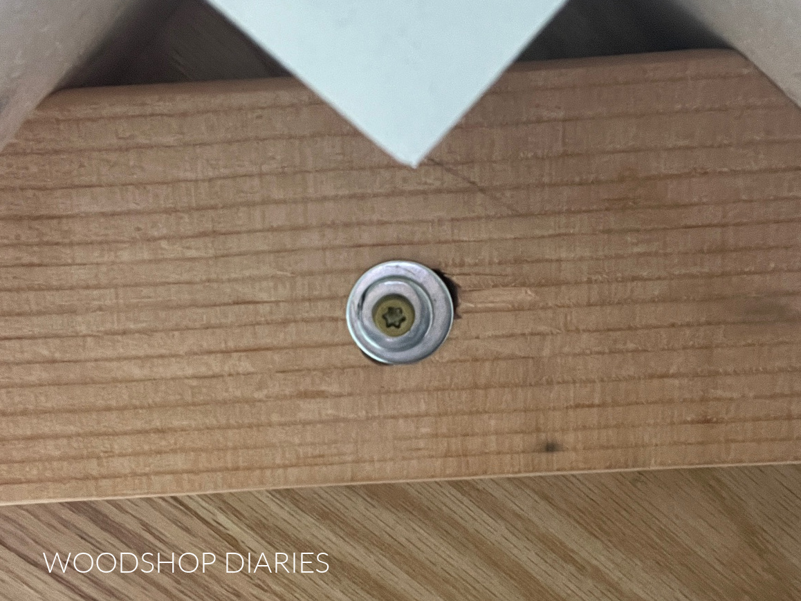 View from underside of table where screw is used through slotted hole to attach table top