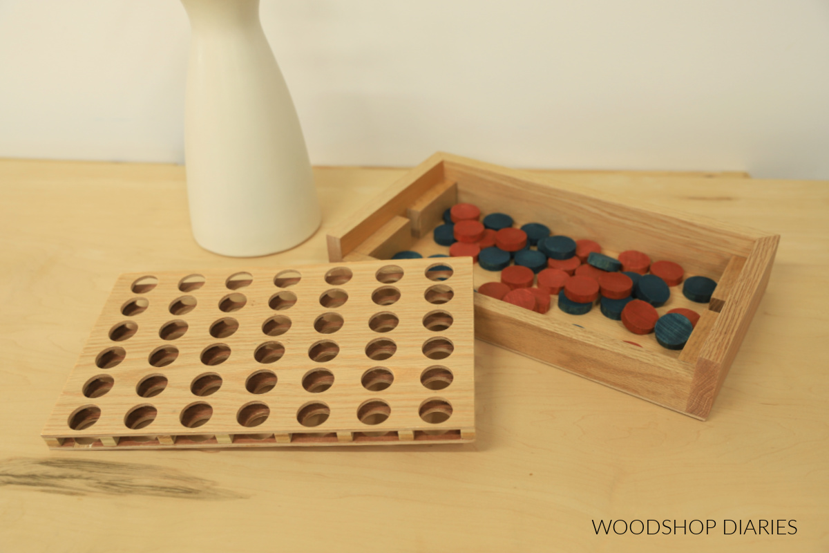 4 in a row game showing storage box with game pieces and game board laying next to it