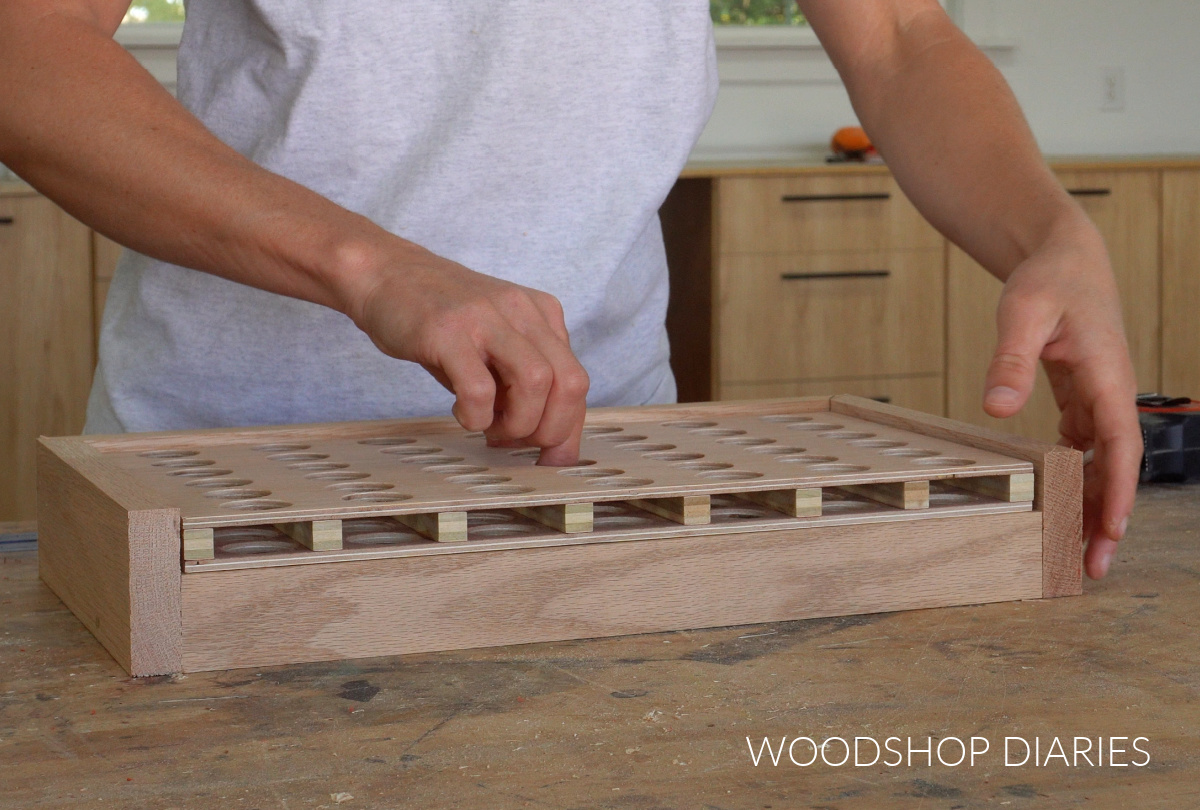 Shara Woodshop Diaries test fitting game board into storage box on workbench for connect 4 game