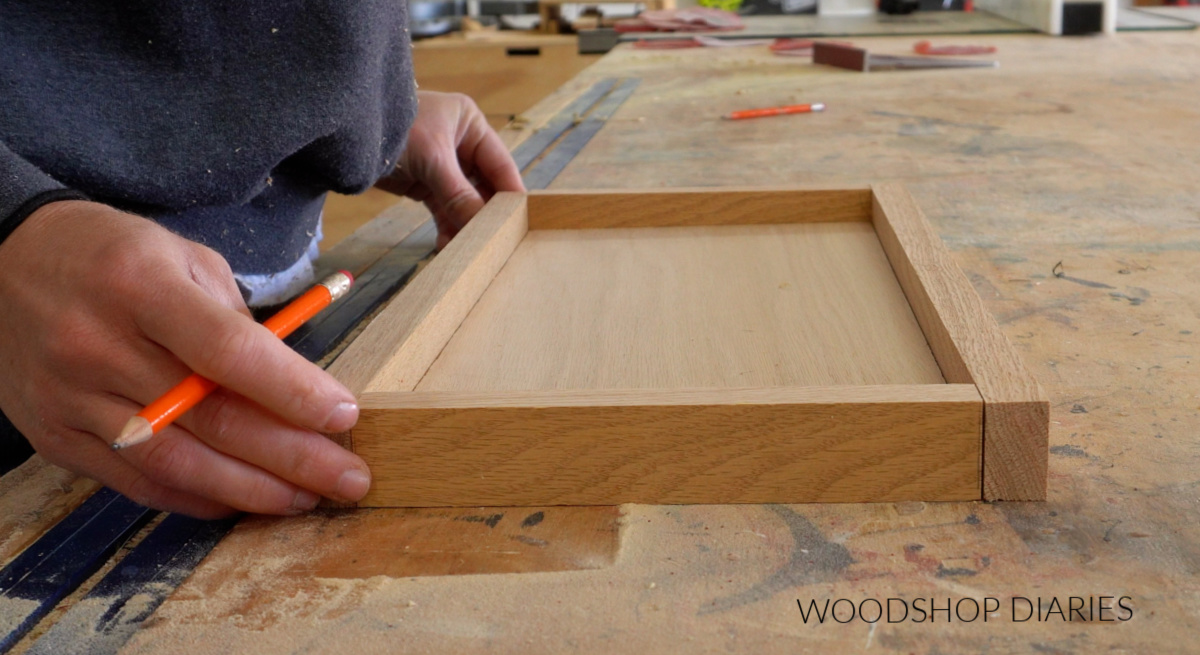 Shara Woodshop Diaries dry fitting pieces of 1x2 around plywood panel on workbench