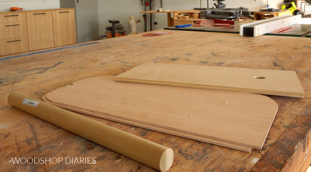 plywood and wood dowel laid out on workbench ready to be cut for DIY connect 4 game build