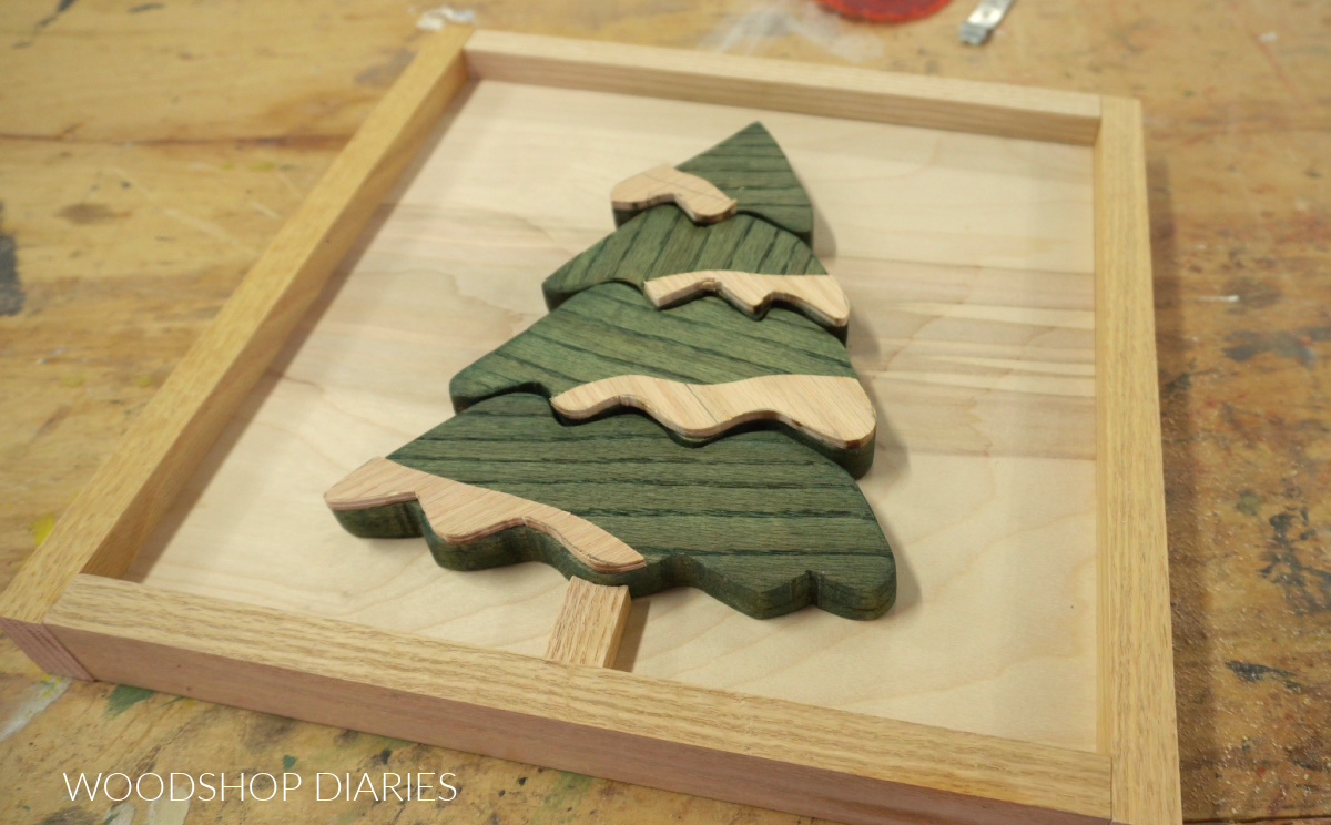 Plywood snow shape cut outs placed on Christmas tree art shape