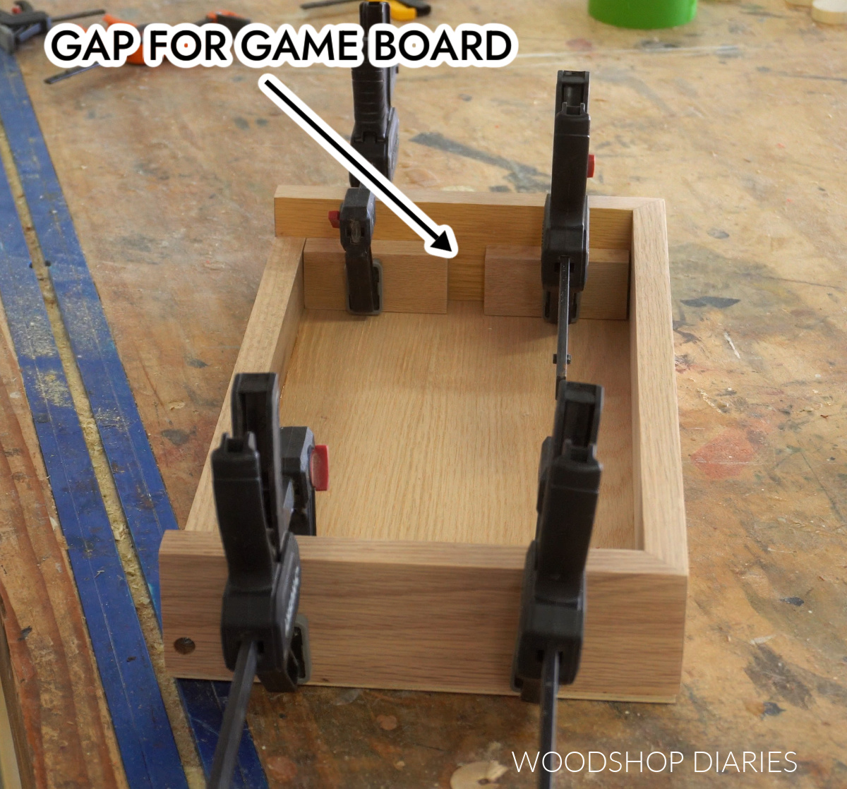 Support pieces glued and clamped into storage box to hole game board vertically