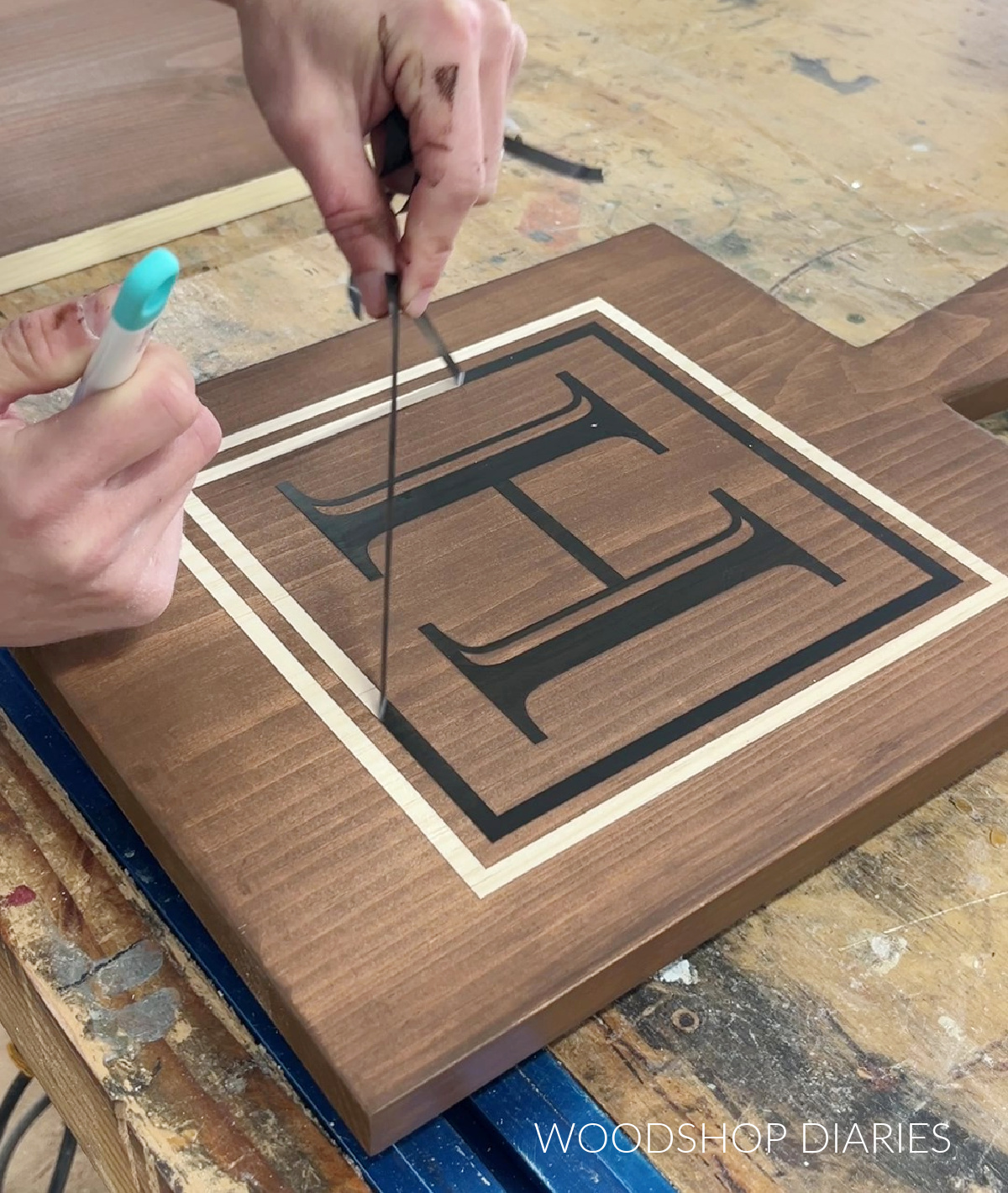 Close up of Shara Woodshop Diaries removing vinyl stencil from serving board