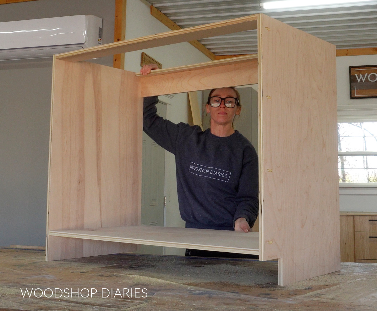 Shara Woodshop Diaries placing assembled cabinet box on workbench in workshop