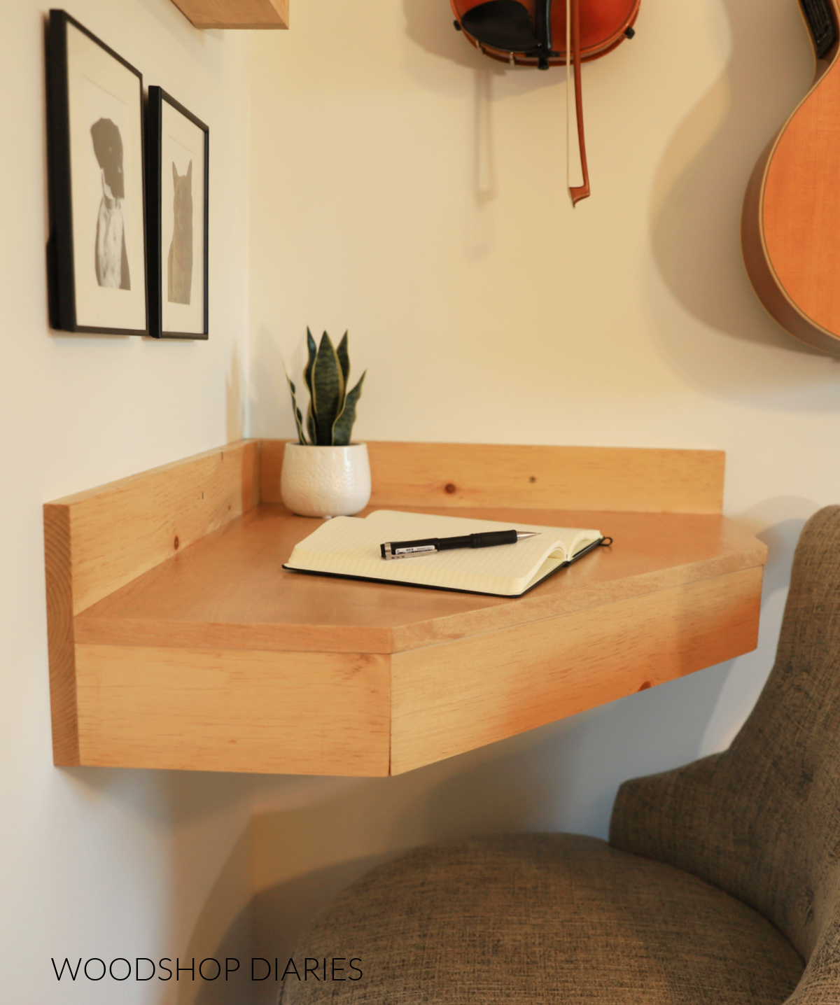 Completed DIY floating corner desk hung on wall with notebook on top