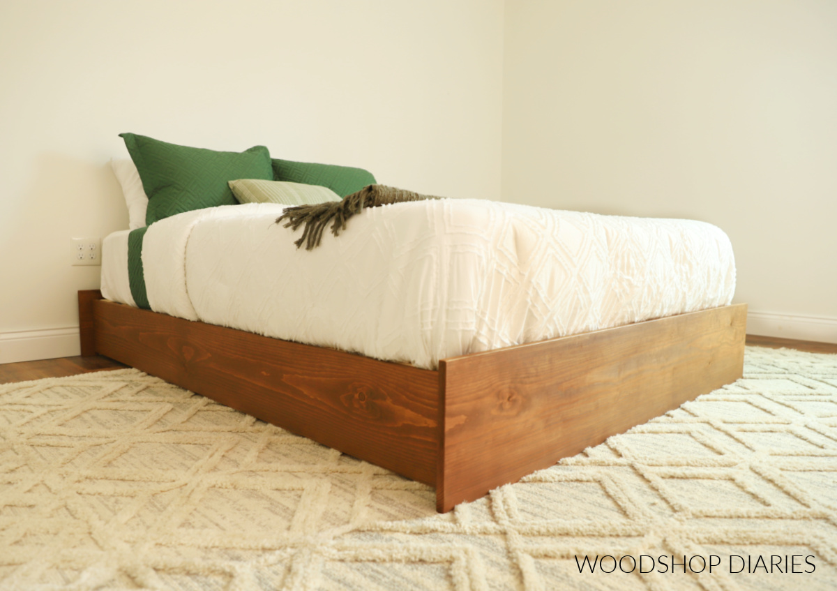Finished platform bed frame assembled in bedroom with mattress on top with white bedding--simple modern bed frame 