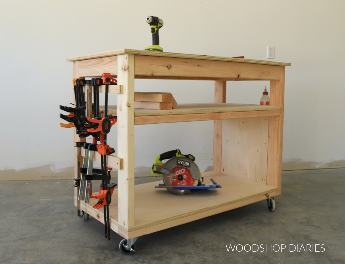 Completed DIY small space workbench with caster wheels, a shelf, and tool storage on both sides--clamp rails with clamps on the left